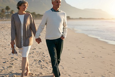 Man and woman walking down beach while holding hands